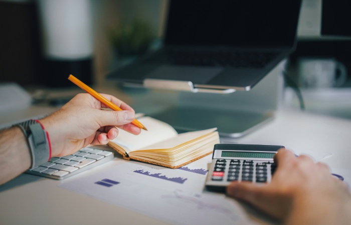 Person calculating debt to income ratio using a calculator and financial documents